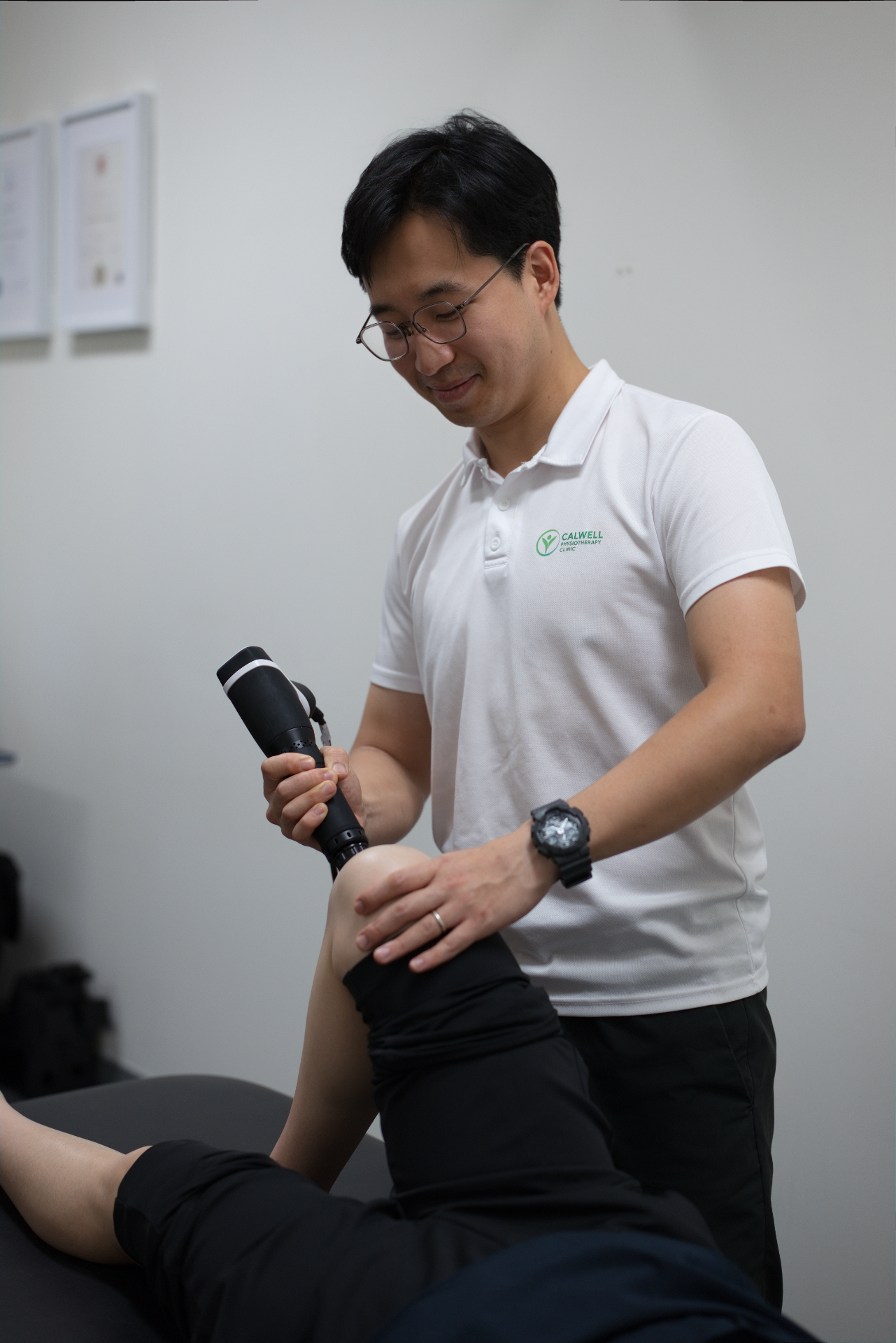 Physiotherapist performing shockwave therapy on a patient's Achilles tendon